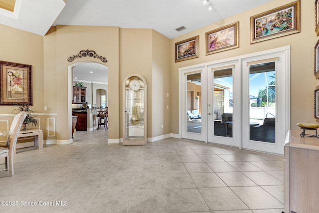 empty room with visible vents, french doors, arched walkways, light tile patterned floors, and baseboards