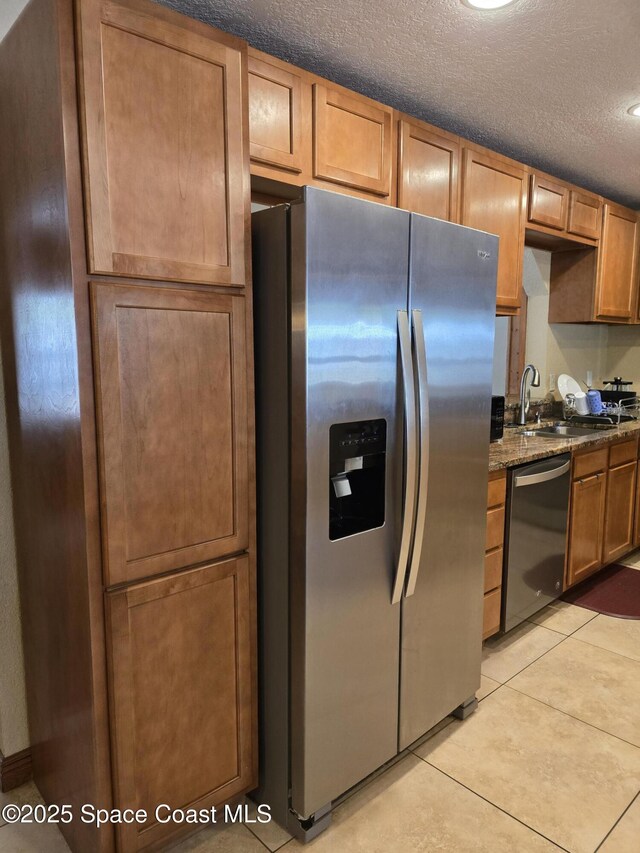 2013 Rollins Dr, Cocoa, FL 32922 - kitchen featuring stainless steel appliances, a sink, dark stone counters, light tile patterned flooring, and a textured ceiling
