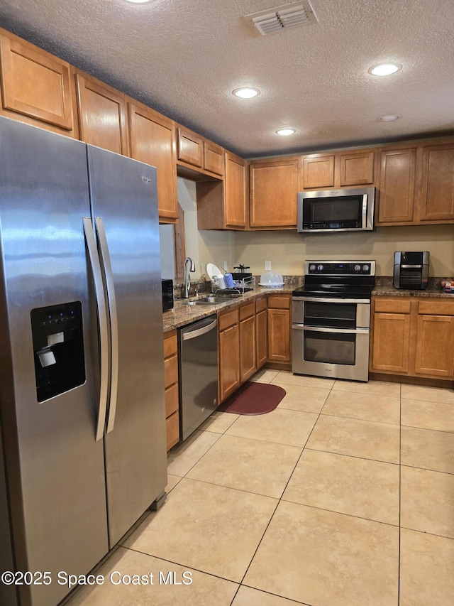 2013 Rollins Dr, Cocoa, FL 32922 - kitchen with appliances with stainless steel finishes, a sink, a textured ceiling, brown cabinetry, and recessed lighting