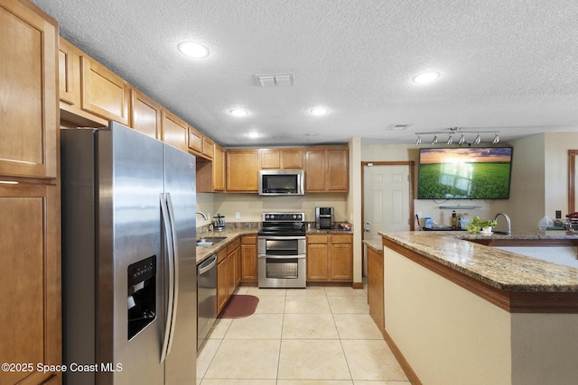 2013 Rollins Dr, Cocoa, FL 32922 - kitchen with stainless steel appliances, a textured ceiling, a sink, recessed lighting, and light stone counters