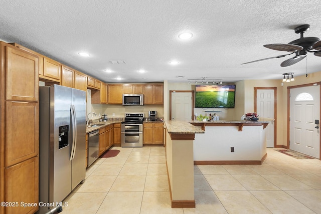 2013 Rollins Dr, Cocoa, FL 32922 - kitchen with appliances with stainless steel finishes, a sink, a kitchen bar, light stone countertops, and light tile patterned flooring