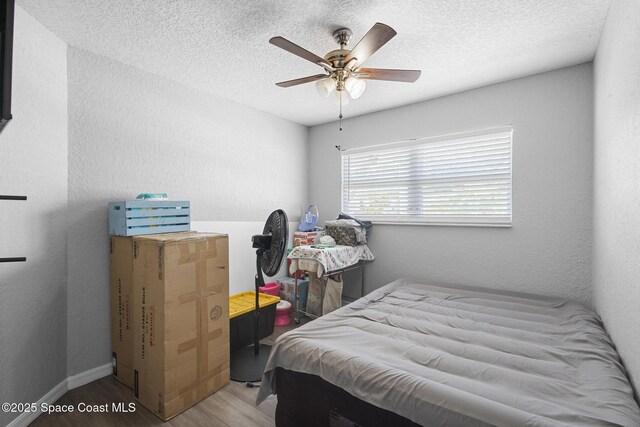 2013 Rollins Dr, Cocoa, FL 32922 - bedroom featuring wood finished floors, a textured ceiling, ceiling fan, and baseboards