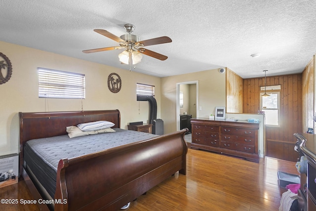 2013 Rollins Dr, Cocoa, FL 32922 - bedroom with wood finished floors, a textured ceiling, a ceiling fan, and wood walls