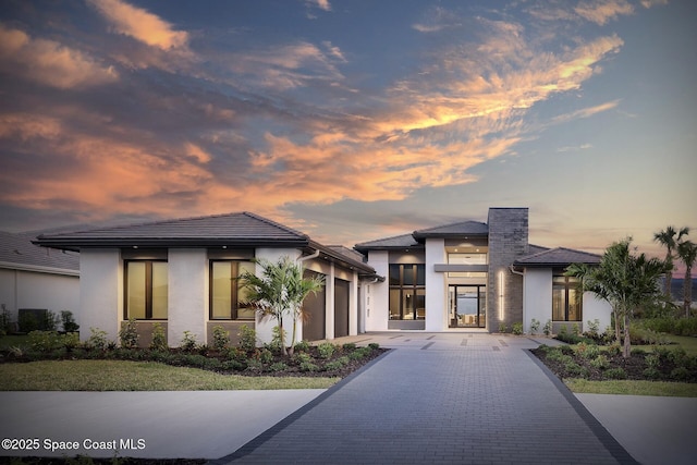 view of front of home featuring driveway, an attached garage, and stucco siding