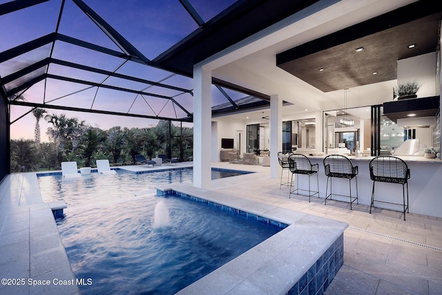 pool with an outdoor hot tub, glass enclosure, a patio, and outdoor dry bar