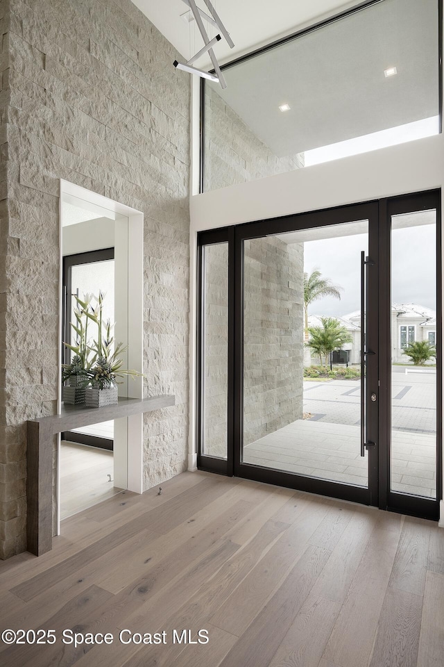 entryway with french doors, a high ceiling, wood-type flooring, and a wealth of natural light