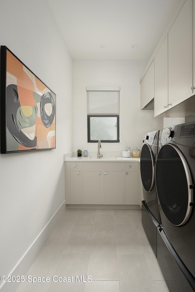 clothes washing area featuring light tile patterned flooring, a sink, baseboards, cabinet space, and washing machine and clothes dryer