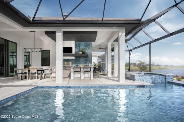 view of pool featuring an outdoor kitchen, a ceiling fan, glass enclosure, outdoor dry bar, and a patio area