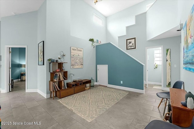 interior space featuring tile patterned flooring, a towering ceiling, and baseboards