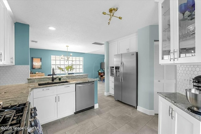 kitchen featuring light stone counters, a sink, visible vents, white cabinets, and appliances with stainless steel finishes