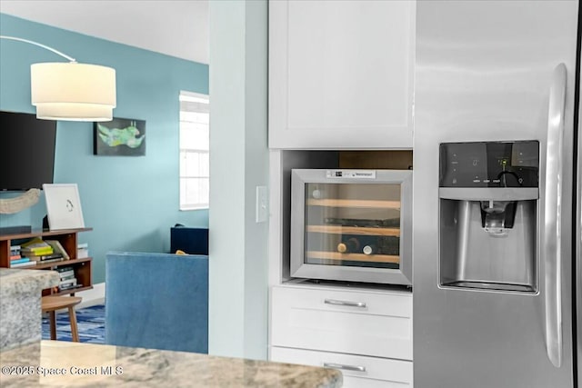 kitchen featuring light stone countertops, beverage cooler, stainless steel fridge, and white cabinets