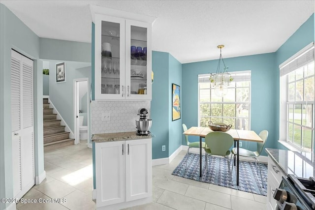 dining room featuring light tile patterned floors, a textured ceiling, a chandelier, baseboards, and stairs