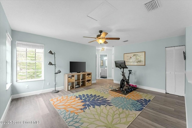 exercise room with baseboards, visible vents, and wood finished floors