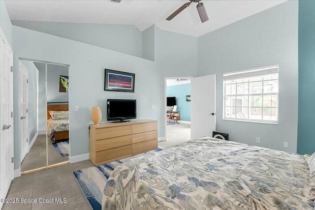 tiled bedroom with high vaulted ceiling, a ceiling fan, and baseboards