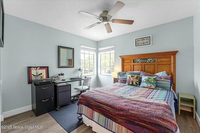 bedroom with a ceiling fan, a textured ceiling, baseboards, and wood finished floors