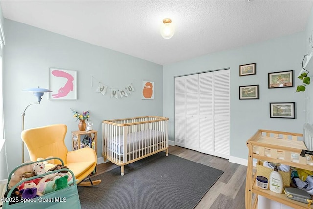 bedroom with a textured ceiling, a closet, baseboards, and wood finished floors