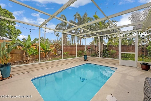 view of pool with glass enclosure, a patio, a fenced backyard, and a fenced in pool