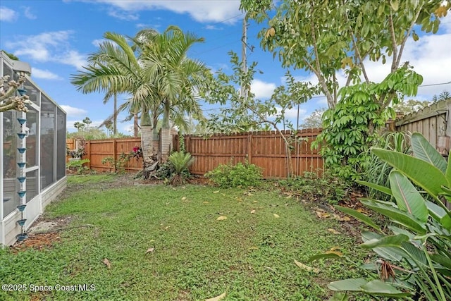 view of yard with a fenced backyard and a lanai