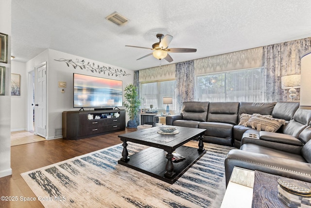 living room featuring a textured ceiling, wood finished floors, visible vents, and a ceiling fan