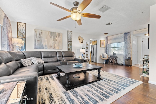 living room featuring visible vents, a textured ceiling, and wood finished floors