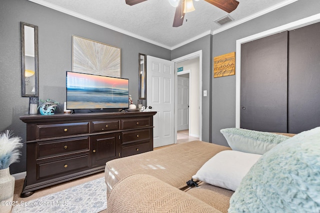 bedroom with visible vents, a ceiling fan, ornamental molding, a textured ceiling, and a closet