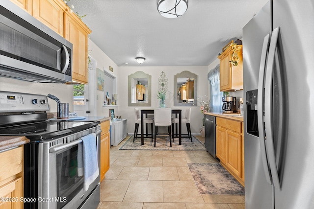 kitchen featuring appliances with stainless steel finishes, light countertops, light brown cabinets, and light tile patterned floors