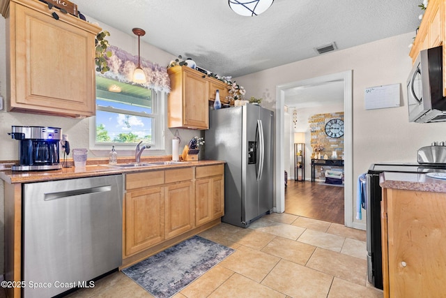 kitchen with visible vents, appliances with stainless steel finishes, light brown cabinetry, a sink, and light tile patterned flooring