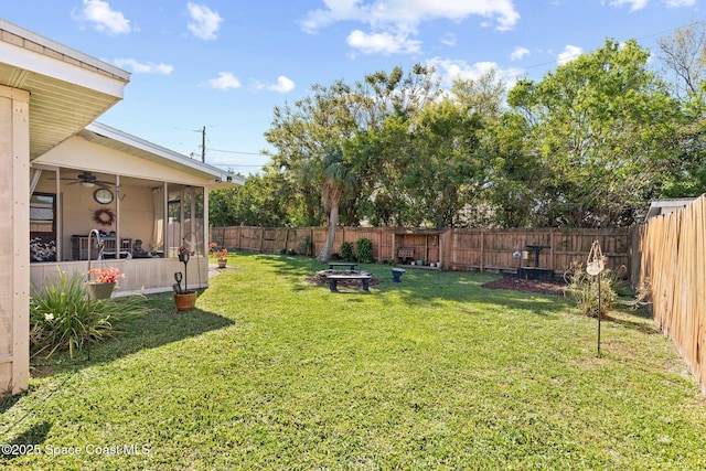 view of yard with a sunroom, a fenced backyard, and a fire pit