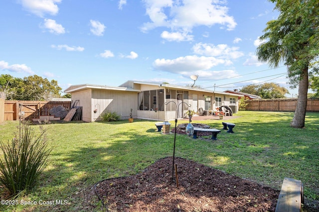 rear view of house featuring a sunroom, a fenced backyard, and a lawn