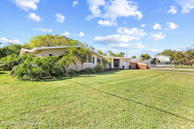 view of front of home featuring stucco siding, an attached garage, a front lawn, and fence