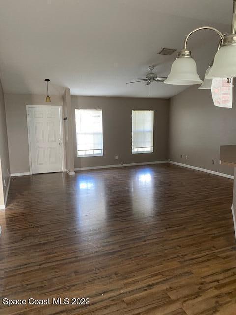 spare room with a ceiling fan, visible vents, baseboards, and wood finished floors