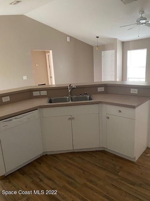 kitchen featuring dishwasher, a sink, white cabinetry, and lofted ceiling