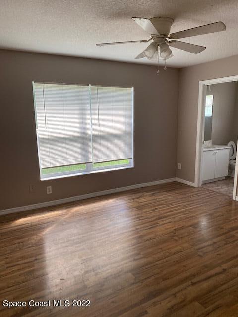 spare room featuring a textured ceiling, ceiling fan, wood finished floors, and baseboards