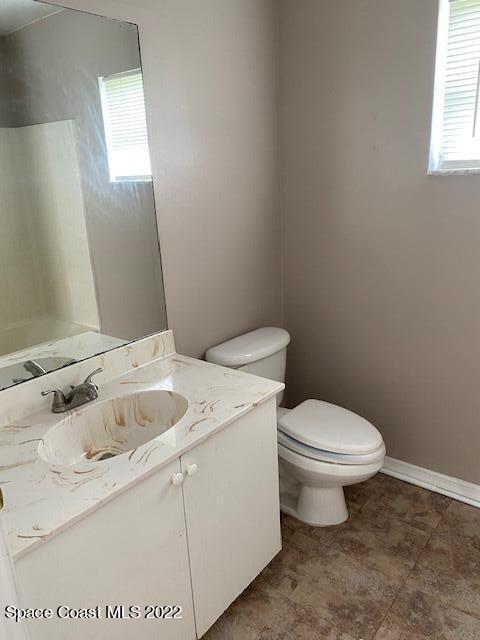 bathroom featuring toilet, baseboards, a wealth of natural light, and vanity