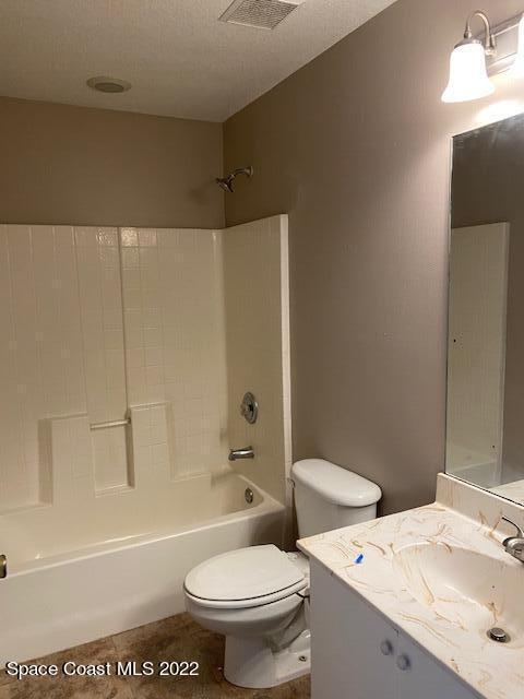 bathroom featuring visible vents, toilet, a textured ceiling, vanity, and washtub / shower combination