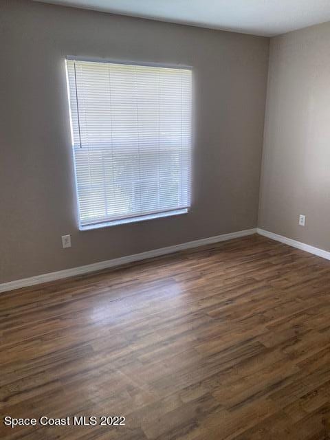 unfurnished room with dark wood-type flooring and baseboards