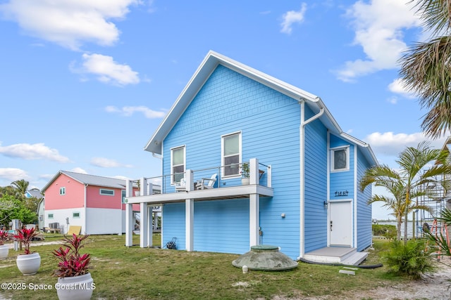 back of property with a lawn and a balcony