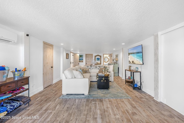 living area featuring a wall mounted air conditioner, a textured ceiling, baseboards, and wood finished floors