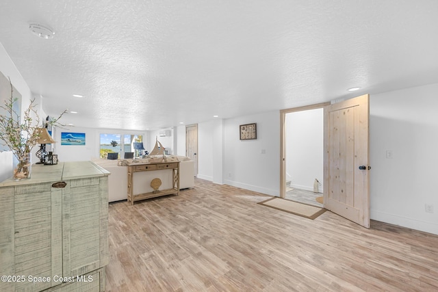 interior space with light wood-style flooring, baseboards, and a textured ceiling