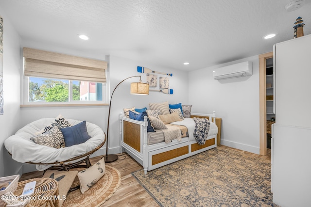 bedroom with recessed lighting, baseboards, an AC wall unit, and wood finished floors