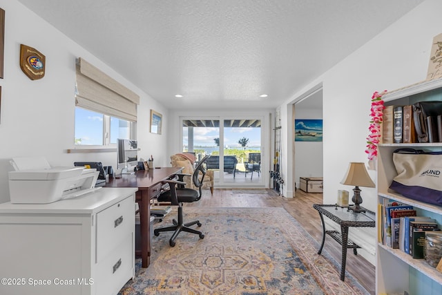 office space with a textured ceiling, wood finished floors, and a healthy amount of sunlight