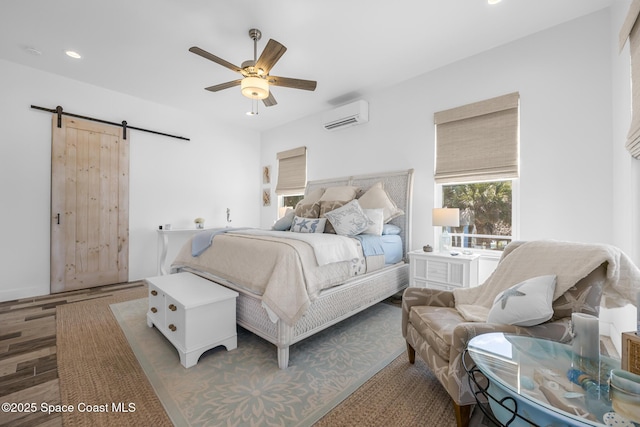 bedroom featuring a barn door, a wall unit AC, ceiling fan, wood finished floors, and recessed lighting