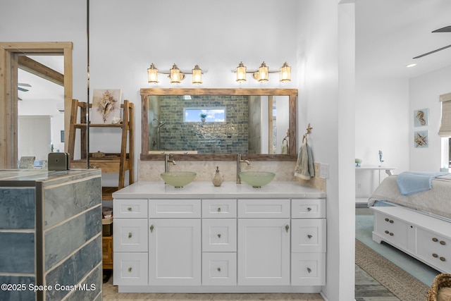 bathroom with double vanity, backsplash, a sink, and tiled shower