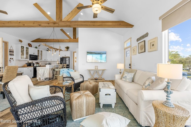 living room with ceiling fan, high vaulted ceiling, beamed ceiling, and wood finished floors