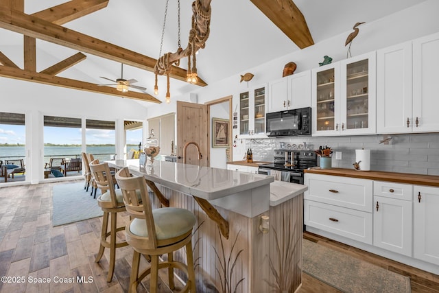 kitchen with black microwave, electric range, beam ceiling, and tasteful backsplash