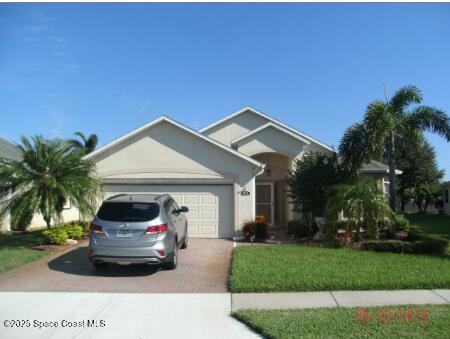 ranch-style house with a front lawn, decorative driveway, an attached garage, and stucco siding