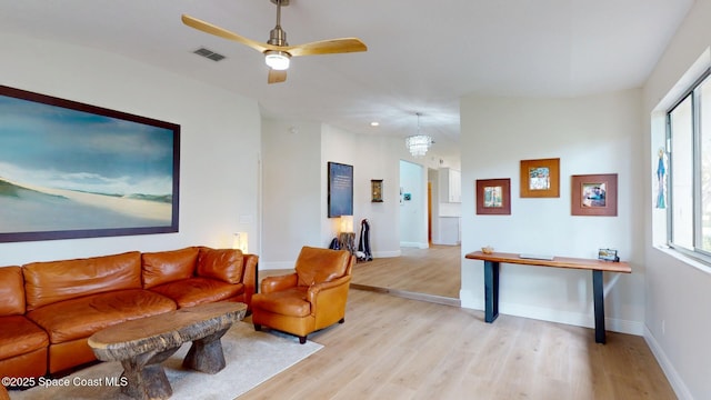 living room featuring a ceiling fan, light wood-type flooring, visible vents, and baseboards