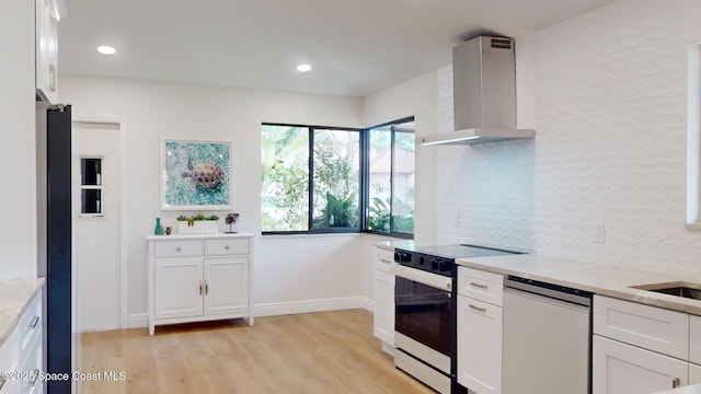 kitchen featuring electric range, tasteful backsplash, dishwasher, light wood-type flooring, and wall chimney range hood