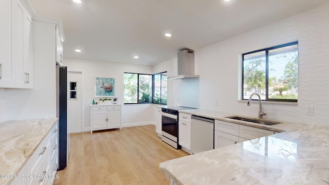 kitchen with light stone counters, electric stove, a sink, wall chimney range hood, and dishwashing machine