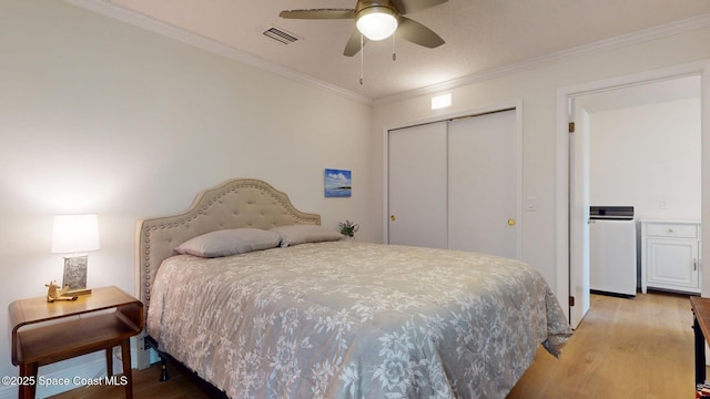 bedroom with ornamental molding, a closet, light wood-type flooring, and visible vents